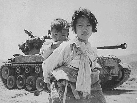 000With her brother on her back a war weary Korean girl tiredly trudges by a stalled M-26 tank, at Haengju, Korea., 1951.jpg